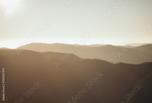 A mountainous landscape with layers of barely visible, golden hills and peaks in the distance.