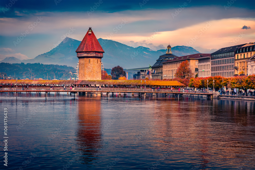 Stunning autumn view of famous old wooden Chapel Bridge (Kapellbrucke), landmark 1300s wooden bridge with grand stone water tower. Pictureasque evening cityscape of Lucerne town, Switzerland.