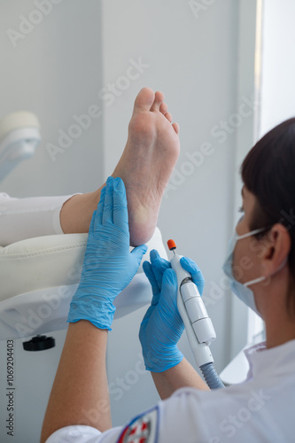The podologist treats the feet using electric device machine. Patient on medical pedicure procedure, visiting podiatrist. Peeling feet. Foot treatment in SPA salon.Podiatry clinic