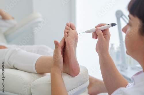 A podologist checks the diabetic  foot  with a Diabetic Foot Probe. Patient on medical pedicure procedure, visiting podiatrist. Peeling feet. Foot treatment in SPA salon.Podiatry