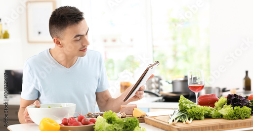 Young man reading recipe bo...