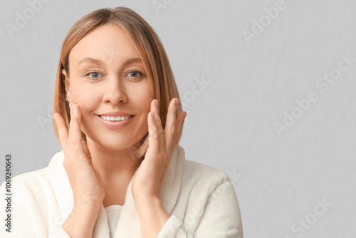 Woman massaging face on grey background