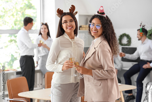 Female colleagues with champagne celebrating New Year at party in office photo