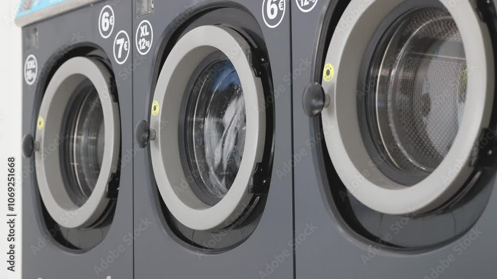 Colored clothes are washed in a washing machine in a laundromat Colored clothes are washed in a washing machine in a laundromat