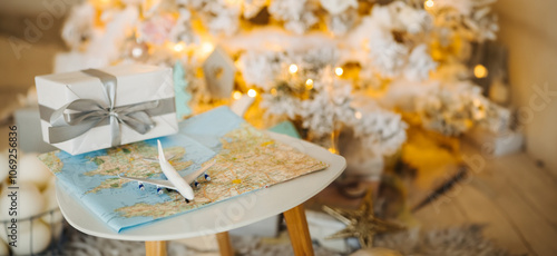 gift for a travel lover. flight as a Christmas present. Toy plane with map with warm New year eve home decorations cozy garlands on Christmas tree