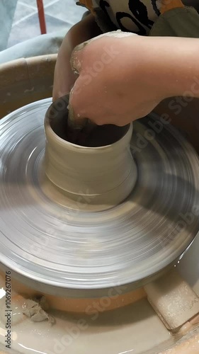 Potter making ceramic plate or plate on pottery wheel. Two hands create bowl. Top view. Potter shapes clay product. Close up 