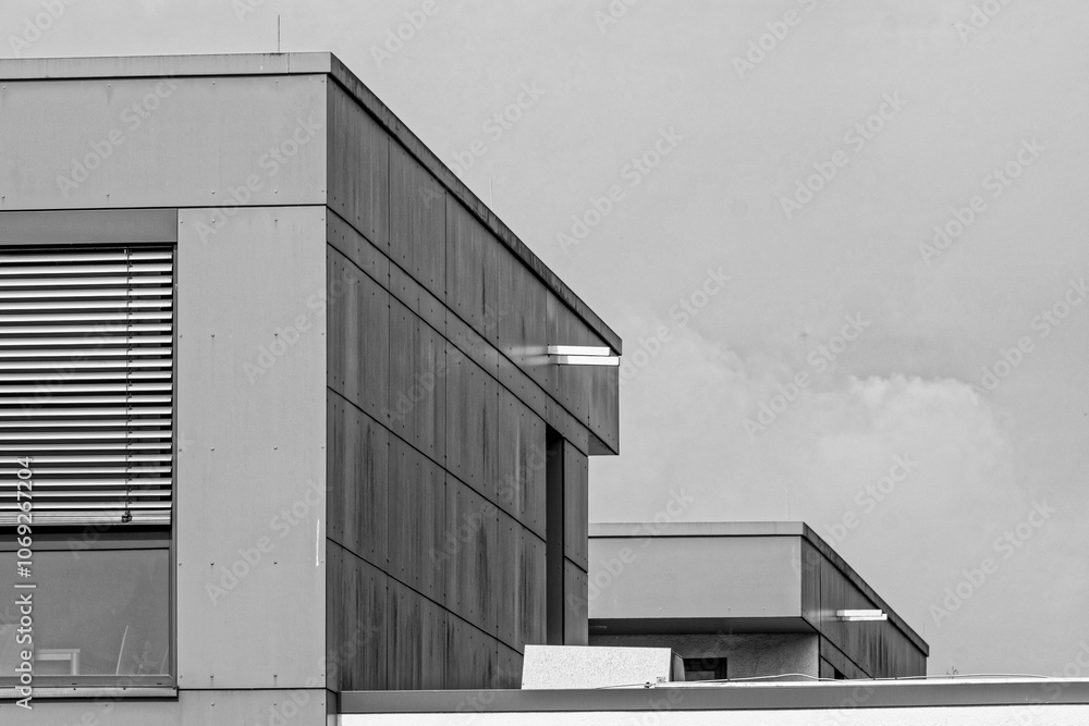 Fototapeta premium Modern architecture showing geometric shapes and a cloudy sky in monochrome