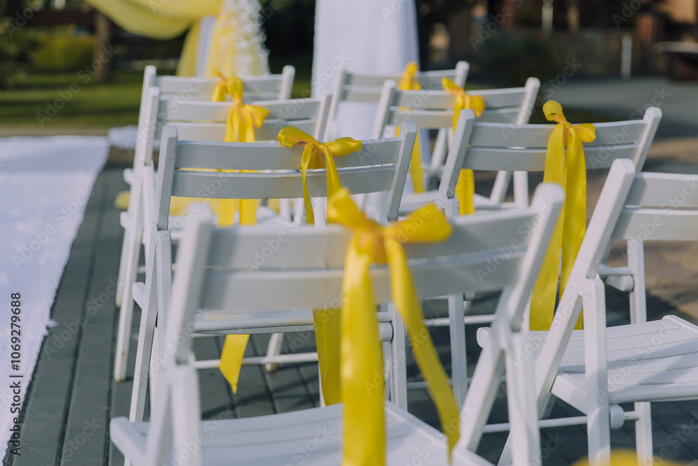 A row of chairs with yellow ribbons tied to them. The chairs are arranged in a row, with some of them facing the camera and others facing away. The yellow ribbons add a pop of color to the scene A row of chairs with yellow ribbons tied to them. The chairs are arranged in a row, with some of them facing the camera and others facing away. The yellow ribbons add a pop of color to the scene