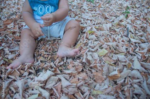 Unrecognizable baby boy sitting in autumn leaves. About 9 months.