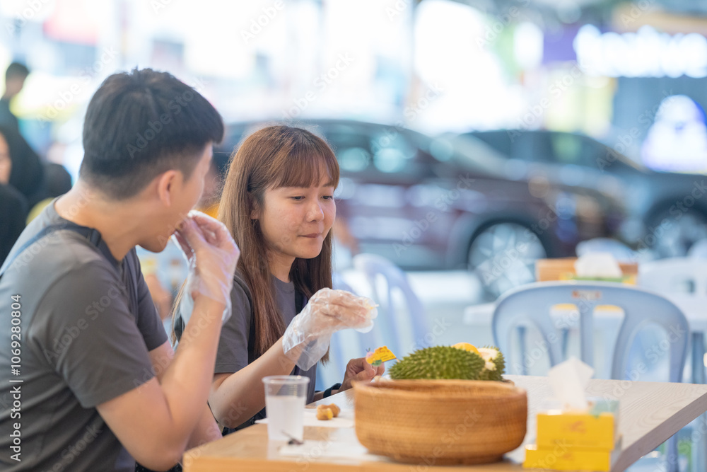 June 2024. A Chinese-Malaysian couple in their 30s chat while eating durian at a famous restaurant popular with tourists in Kuala Lumpur, Malaysia. June 2024. A Chinese-Malaysian couple in their 30s chat while eating durian at a famous restaurant popular with tourists in Kuala Lumpur, Malaysia.