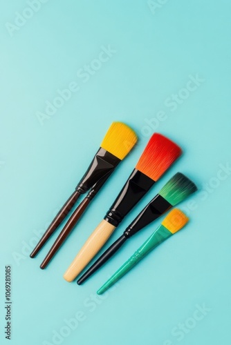 Assortment of colorful makeup brushes on a turquoise background