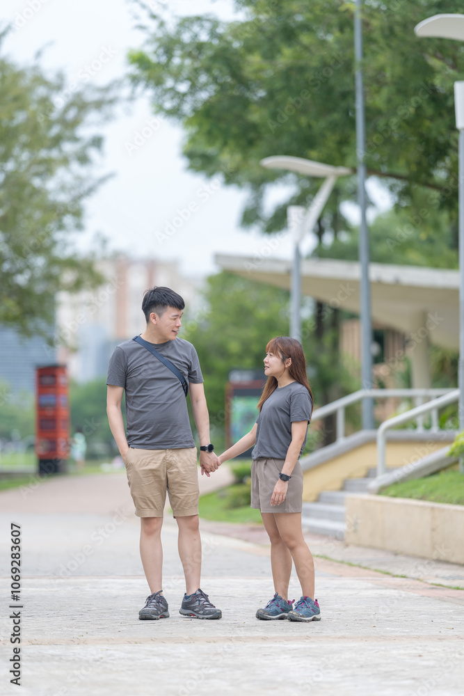 A Chinese-Malaysian couple in their 30s walk together in a green park with abundant water in Kuala Lumpur, Malaysia, on a sunny day in June 2024. A Chinese-Malaysian couple in their 30s walk together in a green park with abundant water in Kuala Lumpur, Malaysia, on a sunny day in June 2024.