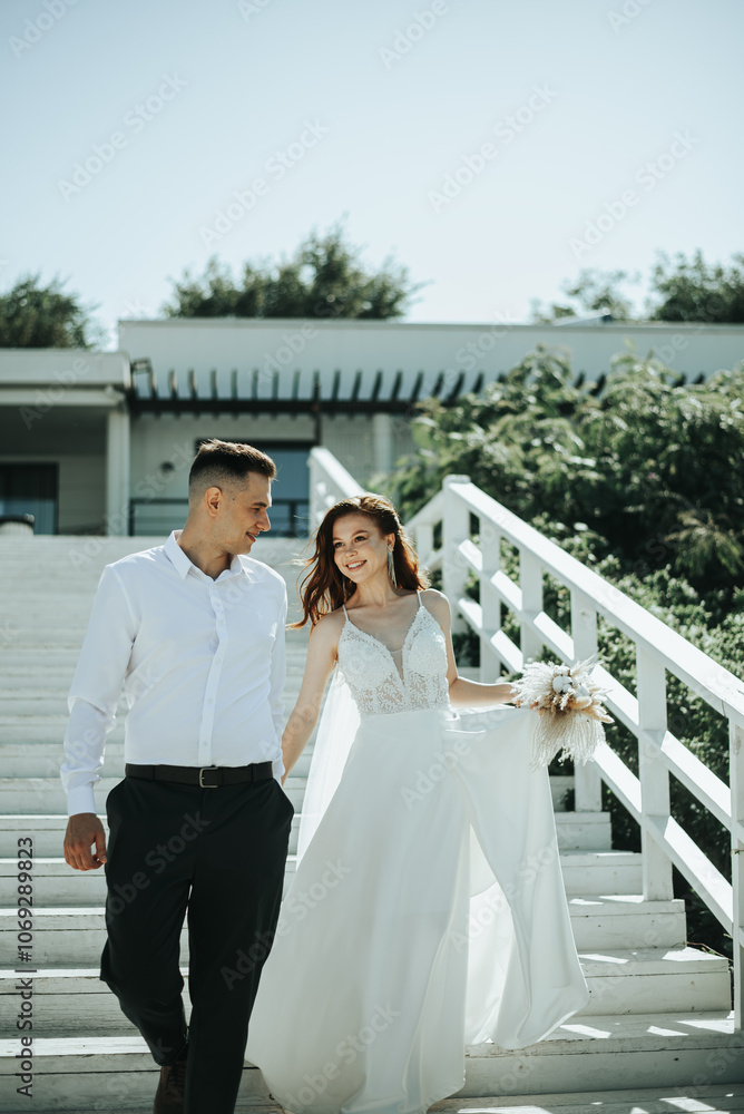 Naklejka premium A bride and groom are walking down a set of white steps