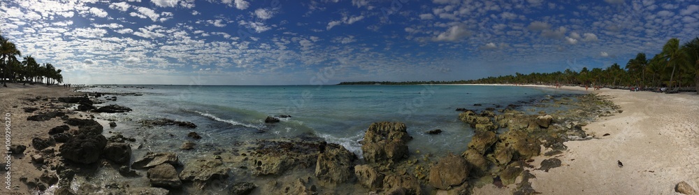 Panoramic view of a picturesque tropical beach with crystal-clear azure waters and a row of swaying palm trees along the shore. Panoramic view of a picturesque tropical beach with crystal-clear azure waters and a row of swaying palm trees along the shore.