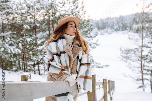 Smiling woman walks near a winter lake. She is enjoying the beautiful winter weather. Nature, travel, winter holidays.