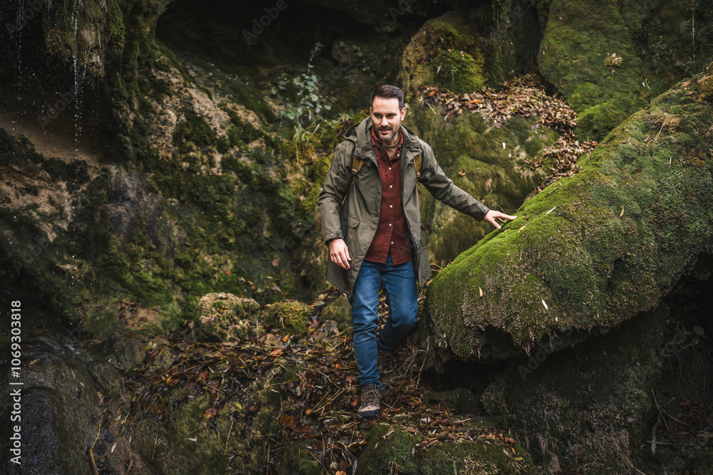 Naklejka premium Adult man hiker walk and explore scenic forest around rocks outdoor
