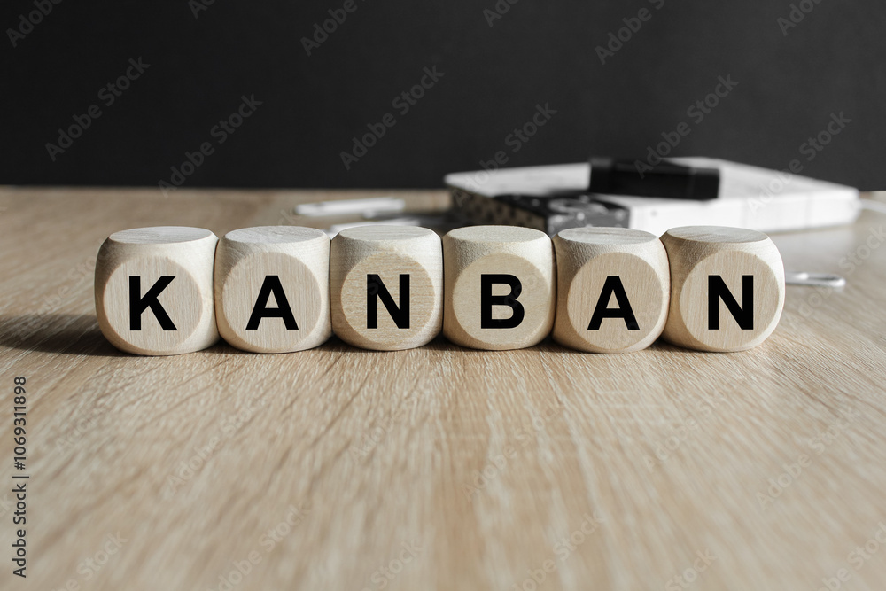 Writing the word KANBAN on wooden cubes. Beautiful wooden table, black background. Info concept.