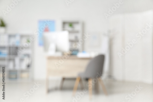 Blurred view of medical office with doctor's workplace and shelf units