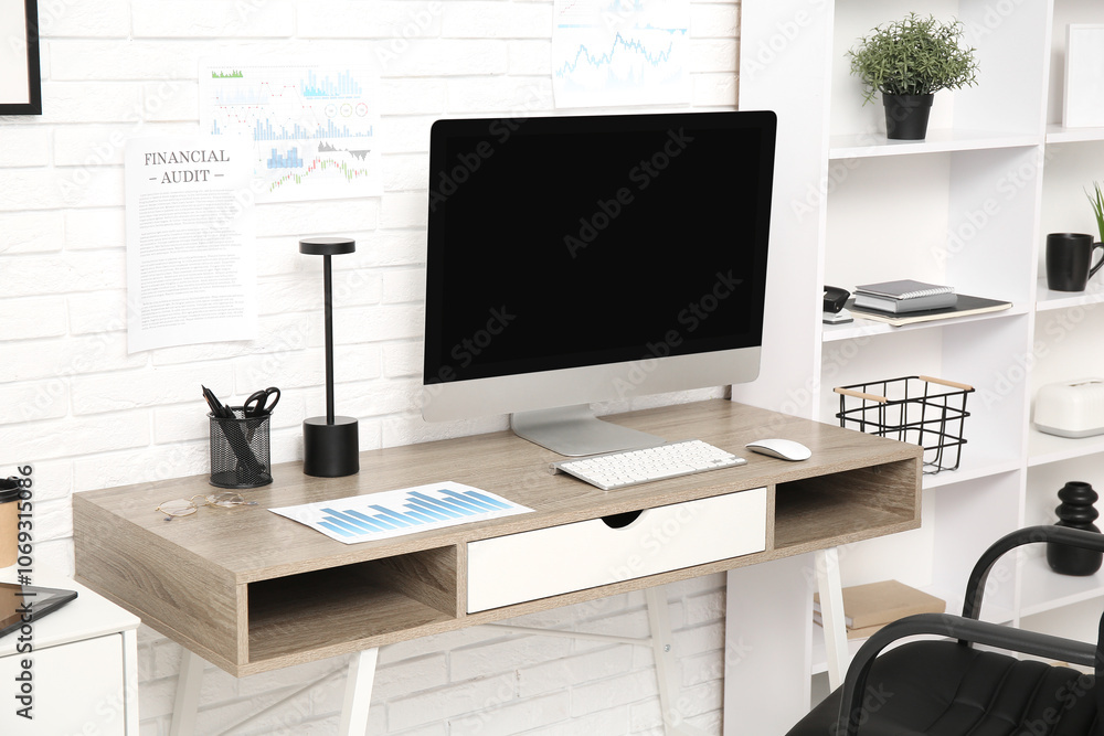 Obraz premium Workplace with blank computer monitor and diagram in office