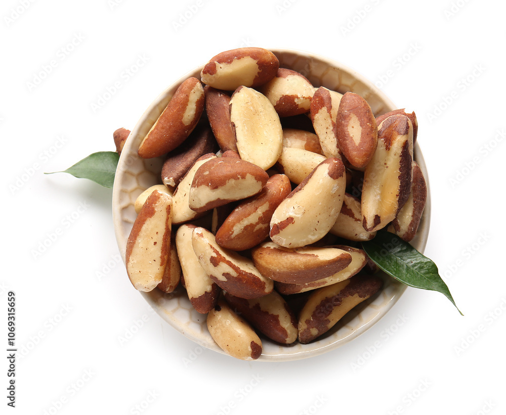 Bowl with tasty Brazil nuts and leaves on white background Bowl with tasty Brazil nuts and leaves on white background