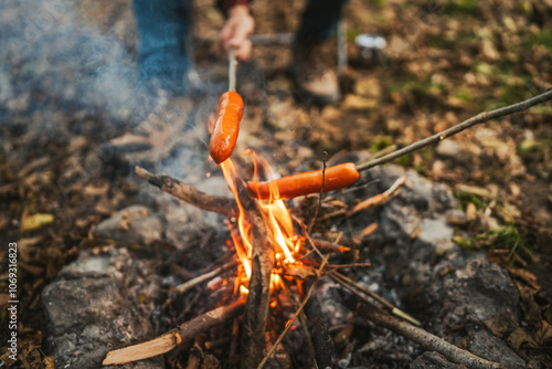 close up of sausage on wood stick grill on the camp fire