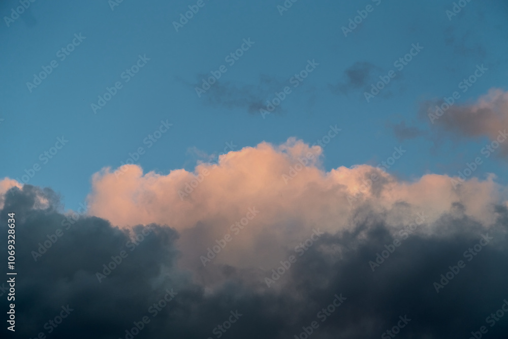Obraz premium Gray-pink clouds in the blue sky illuminated by the setting sun in a close-up shot