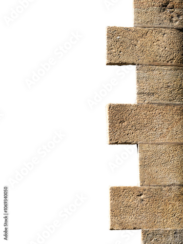 Detail of the corner of a stone wall of an ancient fort, ruins of an old wall of brown stone blocks, corner of the house with a decorative element, Isolated on white background