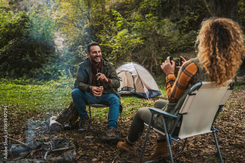 wife take a photo of her husband while he enjoy in front tent