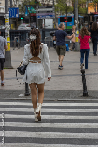 Woman in a white dress walks across a crosswalk