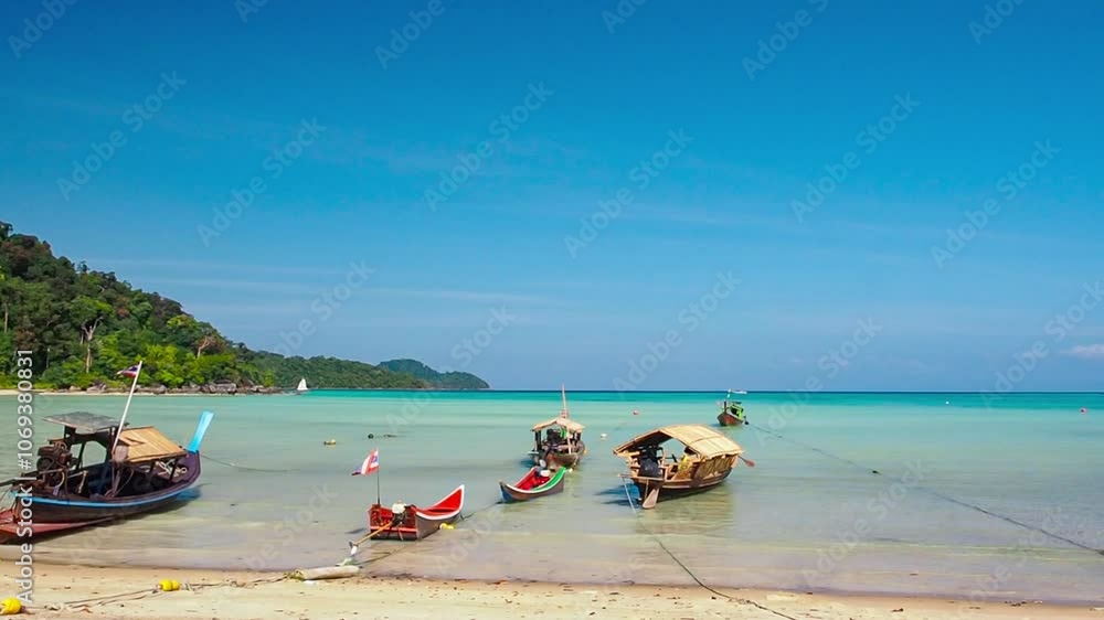Local boats park on the beach with blue sky and green tropical islands. calm ocean water lapping gently on the white sandy beach. aquatic color of the water reflects with sunlight on a sunny day. Local boats park on the beach with blue sky and green tropical islands. calm ocean water lapping gently on the white sandy beach. aquatic color of the water reflects with sunlight on a sunny day.