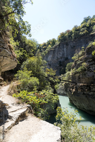 Osumi, Albania - August 15 2024: Small bridge (Ura e Vjeter e Zaberzanit) crossing the Osumi River Canyon. Beautiful views on famous gorge and river. photo