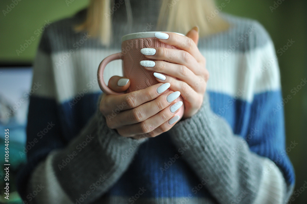 Cozy autumn or winter scene of a woman in a sweater holding a cup of tea, showing elegant manicure. Warm, comforting atmosphere. Cozy autumn or winter scene of a woman in a sweater holding a cup of tea, showing elegant manicure. Warm, comforting atmosphere.