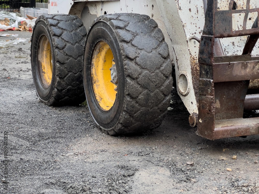 These rugged tires, caked in dirt and gravel, belong to a construction vehicle parked in a bustling urban area undergoing revitalization, showcasing the blend of grit and progress These rugged tires, caked in dirt and gravel, belong to a construction vehicle parked in a bustling urban area undergoing revitalization, showcasing the blend of grit and progress