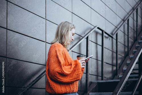 Woman in a Cozy Knitted Orange Sweater Holding Coffee photo