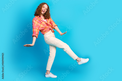 Energetic young woman in casual outfit celebrating against bright blue background