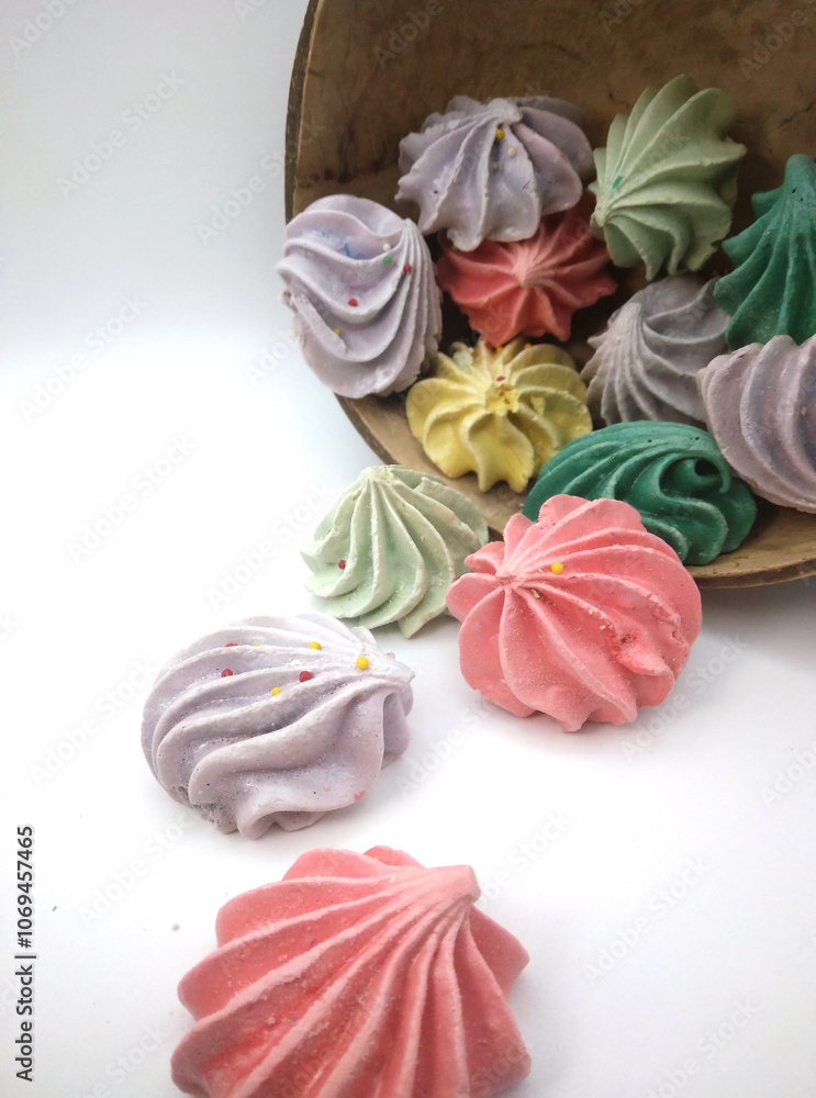 Close up of meringue cookies spilling out of wooden bowl with selective focus Close up of meringue cookies spilling out of wooden bowl with selective focus