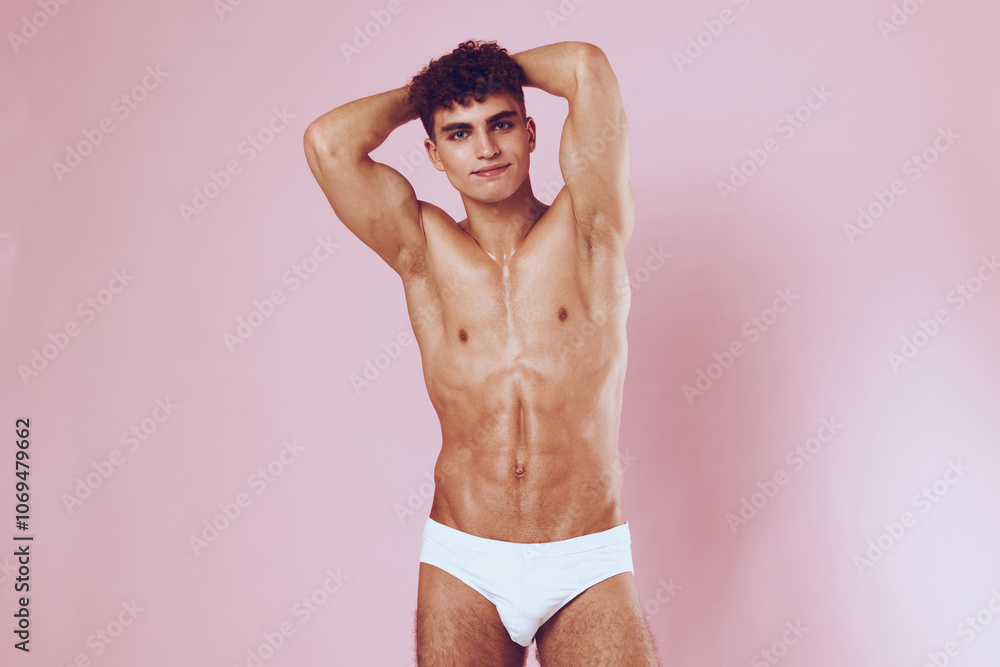 Fototapeta premium Confident young man posing in studio against a pink background. Fitness and health concept highlighting body positivity and self-acceptance.