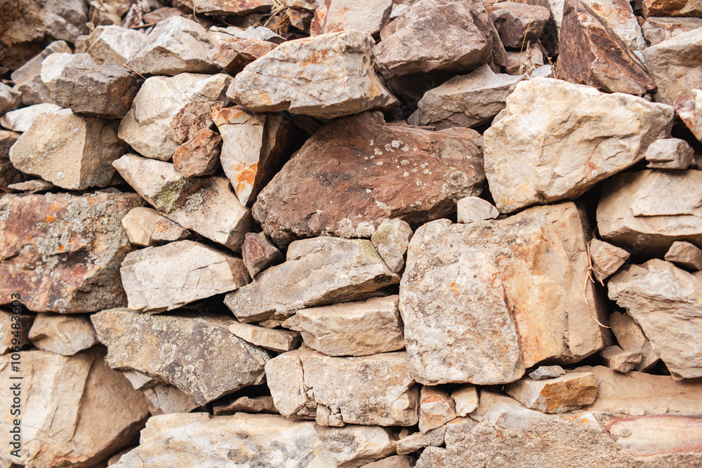 A wall constructed of medium sized stones, arranged one atop the other, featuring a blend of cream and gray hues A wall constructed of medium sized stones, arranged one atop the other, featuring a blend of cream and gray hues