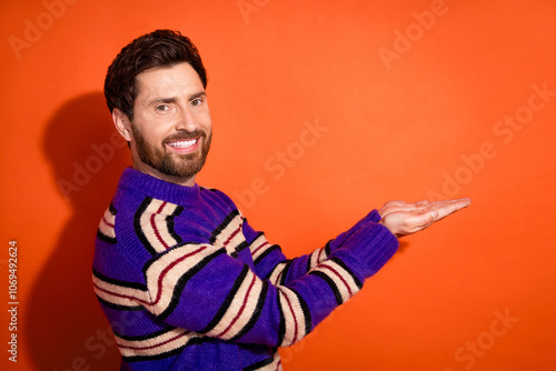 Photo portrait of nice young male hold empty space wear trendy striped violet outfit isolated on orange color background