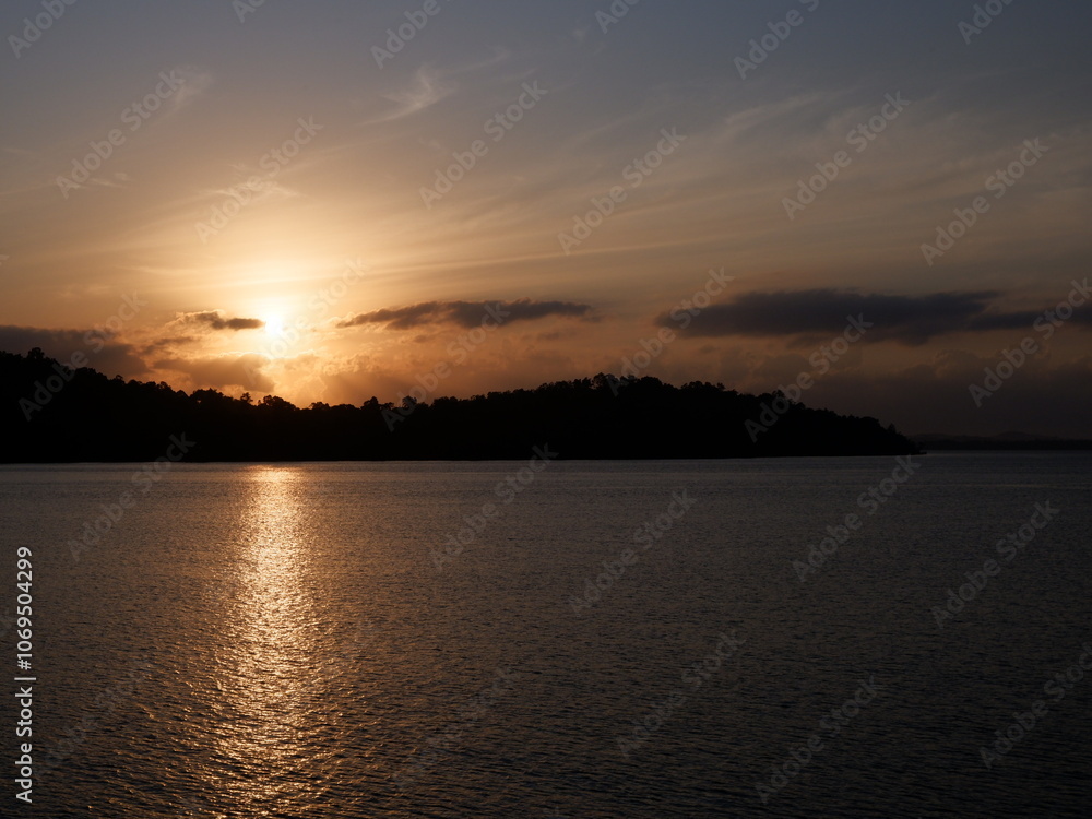 Naklejka premium Stunning sunrise over Kotabaru beach, South Kalimantan, casting golden light on tranquil waters and creating a serene coastal scene