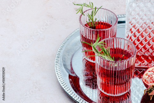 Two beautifully arranged glasses filled with vibrant pomegranate drinks sit on a silver tray. Holiday cocktail for Thanksgiving, Christmas or New Year's Eve. photo