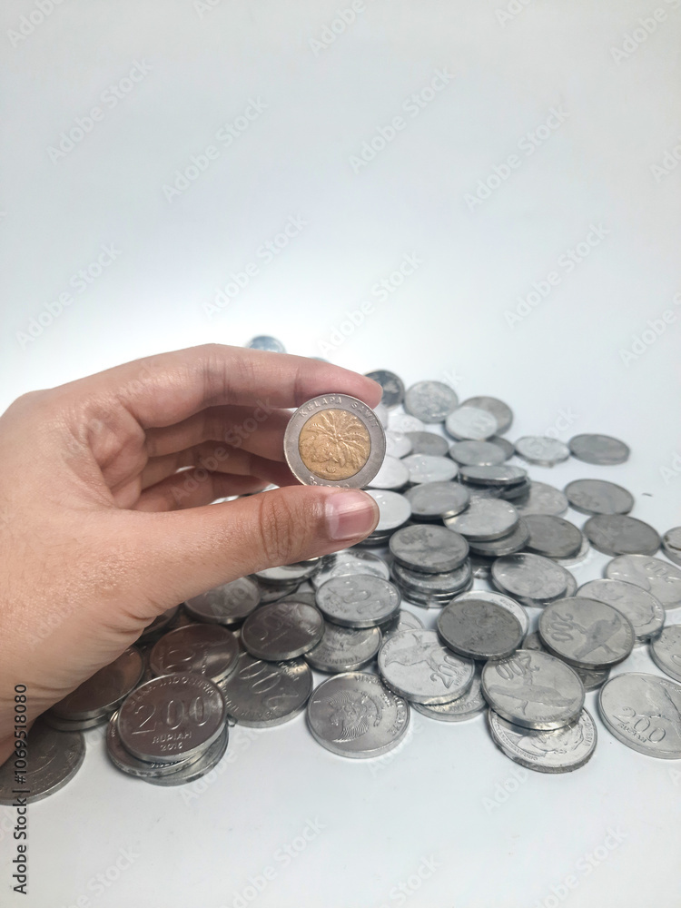 Old rupiah money koin, 1000 rupiah between a stack of other rupiah coins Old rupiah money koin, 1000 rupiah between a stack of other rupiah coins