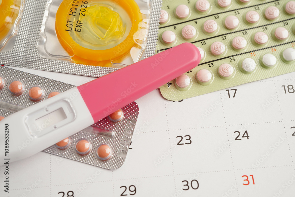 Pregnancy test with birth control pills and condom for female on calendar, ovulation day. Pregnancy test with birth control pills and condom for female on calendar, ovulation day.