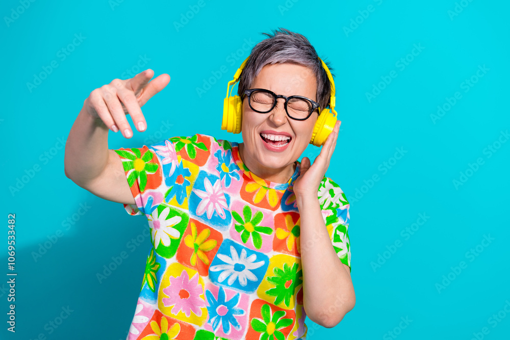 Portrait of pretty aged lady enjoy music headphones wear t-shirt isolated on turquoise color background Portrait of pretty aged lady enjoy music headphones wear t-shirt isolated on turquoise color background