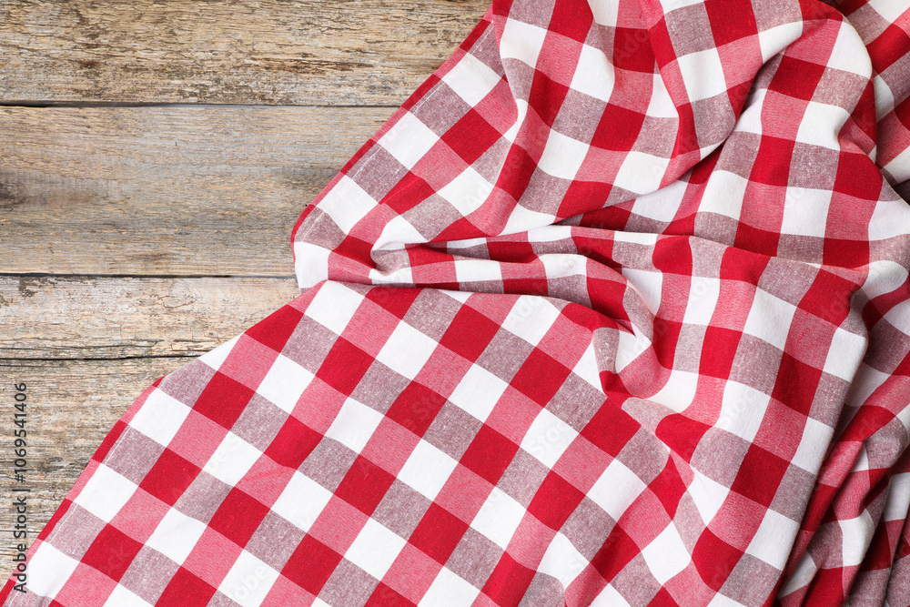 Obraz premium Crumpled tablecloth with checkered pattern on wooden table, top view