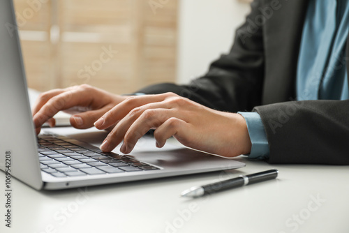 Businesswoman using laptop at white table indoors, closeup. Modern technology