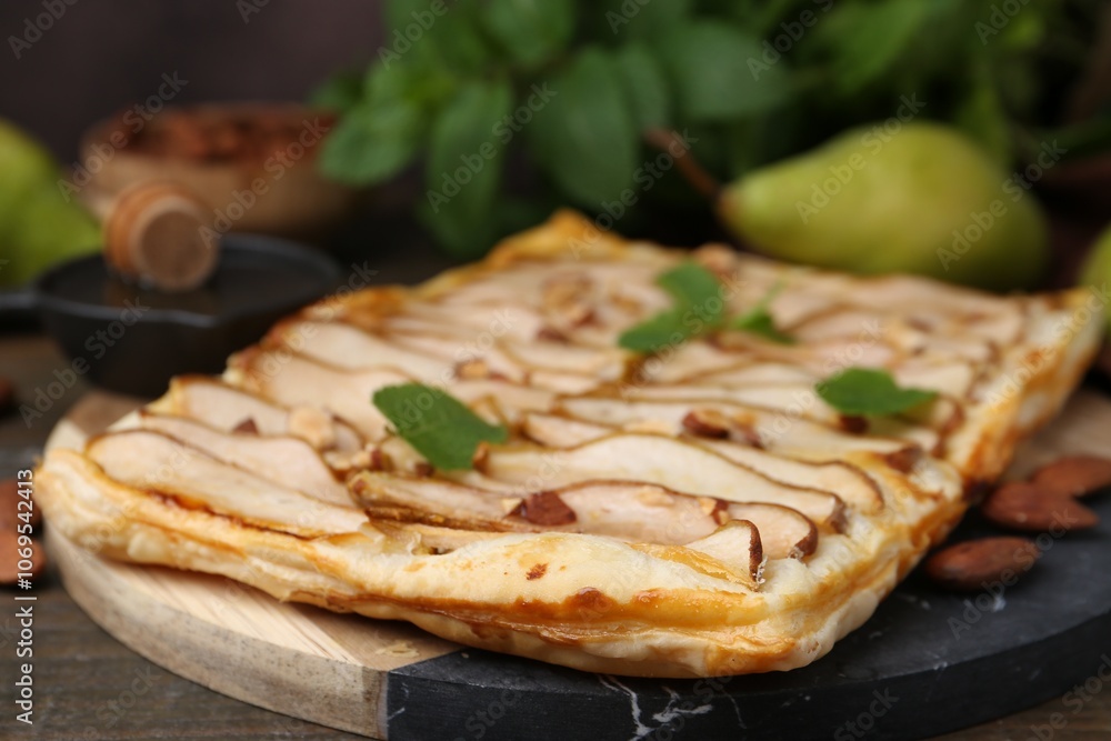 Delicious puff pastry tart with pears, almond and mint on wooden table, closeup Delicious puff pastry tart with pears, almond and mint on wooden table, closeup