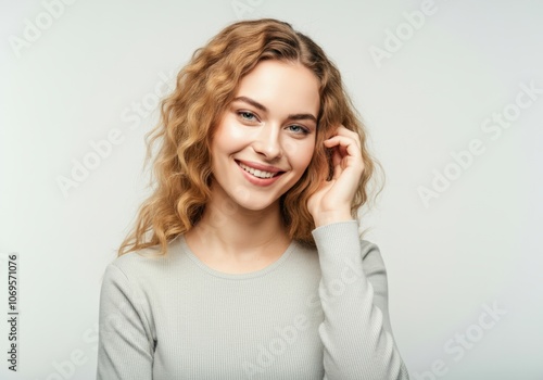 Close-up portrait of smiling woman with curly hair touching her ear