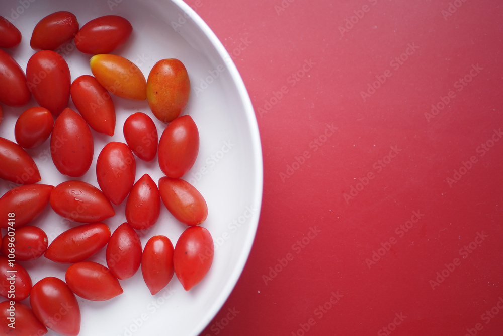 Assorted Cherry Tomatoes arranged on a white plate, with a vibrant red background Assorted Cherry Tomatoes arranged on a white plate, with a vibrant red background