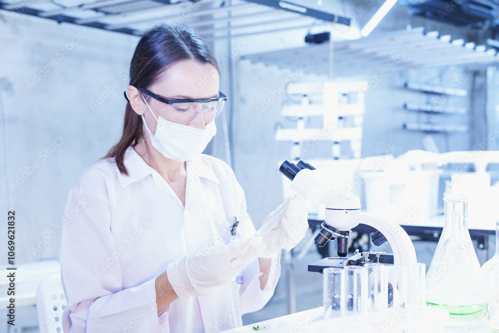 Fototapeta premium Scientist working in high-tech laboratory analyzing specimen under microscope. Ideal for biotechnology, innovation, lab work, and modern science visuals.